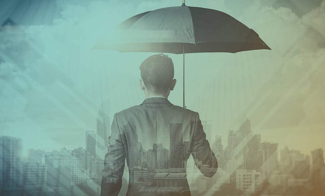 Business executive holds an umbrella and faces towards a cityscape