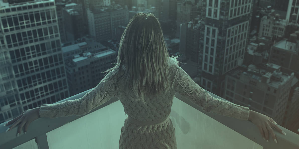 A woman standing on the top of a building looking out on the city