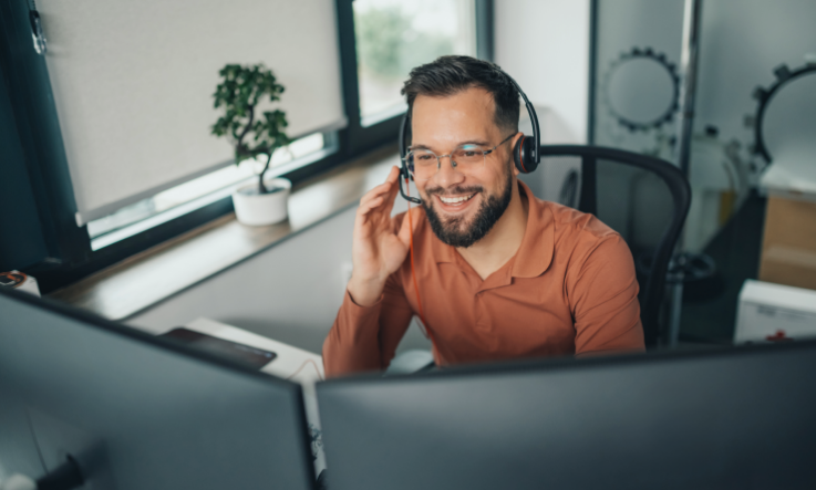 Freight broker with a headset on at his computer.