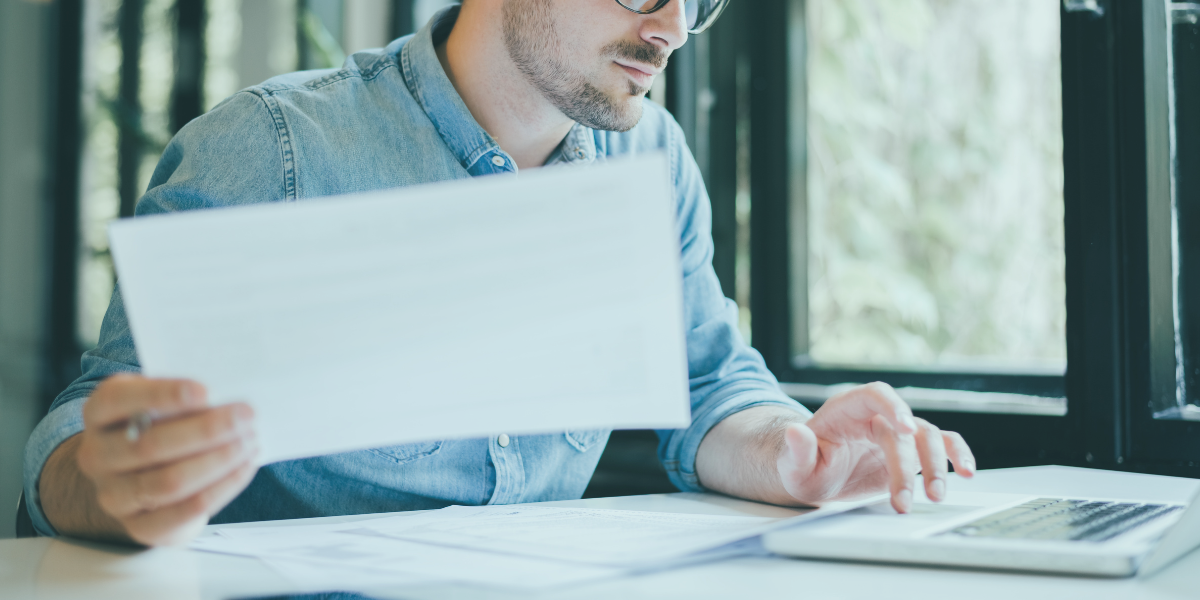 A business owner reviewing financials on his laptop and considering bad debt protection as a solution for his business.