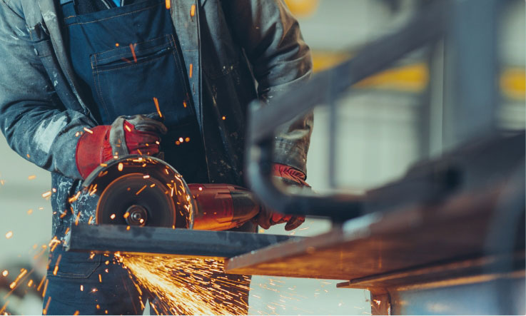 Worker using an angle grinder on metal.
