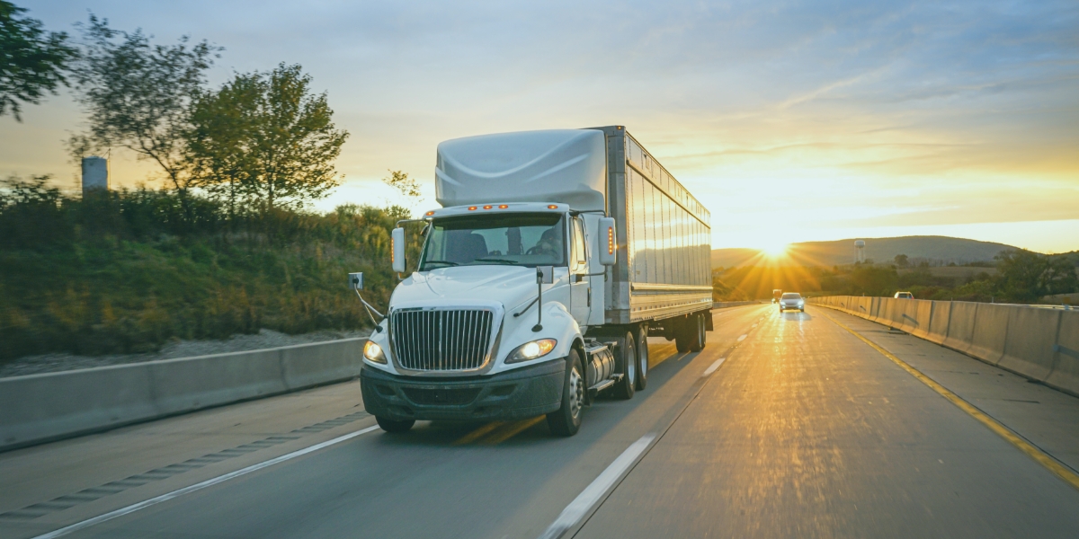 Transport truck driving down the highway during a sunset.