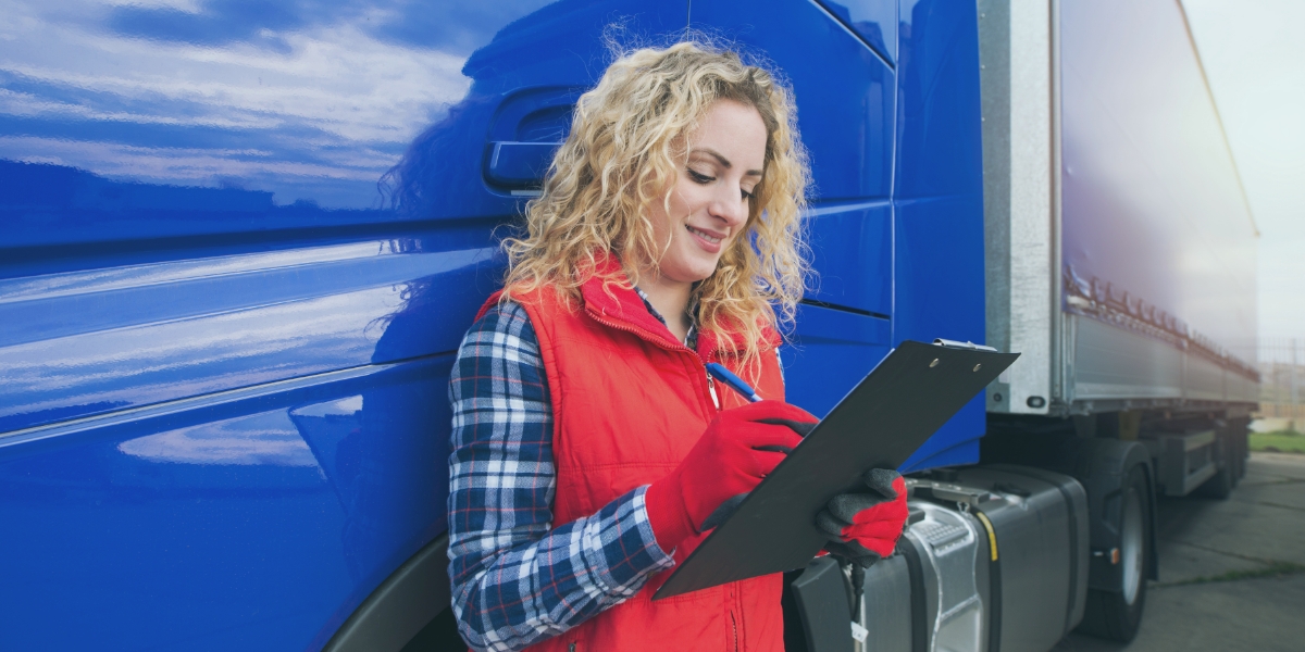 Trucker leaning on her truck reviewing her detention pay paperwork.