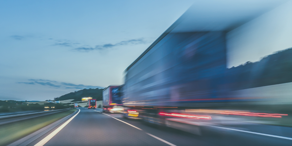 Semi trucks hauling dedicated freight on a highway at dusk